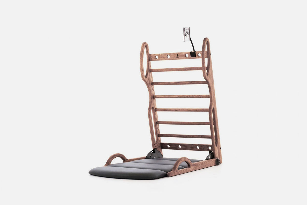 Open stretch station in medium-brown wood with horizontal rungs and a dark fold-out mat